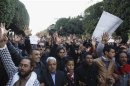 Demonstrators hold up signs and shout slogans outside the interior minister's office in Tunis