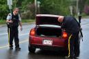 Police officers check a car at a roadblock in Moncton, New Brunswick, on Thursday, June 5, 2014. RCMP officers combed the streets and woods of this normally tranquil city Thursday in search of a man suspected of killing three officers in the deadliest attack on their ranks in nearly a decade. The suspect, 24-year-old Justin Bourque, was armed with high-powered long firearms. He was spotted three times while eluding the massive manhunt that emptied roads and kept families hunkered in their homes in Moncton, an east coast city where gun violence is rare. (AP Photo/The Canadian Press, Andrew Vaughan)
