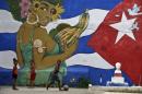 Children play soccer in front of graffiti depicting Cuba's national flag, in Havana