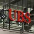 People walk behind the logo of Swiss bank UBS in Zurich