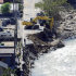 An excavator works at the site where part of a road is washed away by flood water in Nachikatsuura, Wakayama Prefecture, central Japan, Tuesday, Sept. 6, 2011. Typhoon Talas dumped record rain, killing dozens of people in Japan. (AP Photo/Kyodo News) JAPAN OUT, MANDATORY CREDIT, NO LICENSING IN CHINA, FRANCE, HONG KONG, JAPAN AND SOUTH KOREA