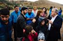 The head of the UN refugee agency Antonio Guterres (R) meets with people on a road shortly after they arrived with other migrants and refugees by boat on the Greek island of Lesbos on October 11, 2015