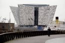 In this photo of Tuesday March 13, 2012 a man walks past the new 100 million British pounds ($157 million)Titanic Belfast Visitor's Center. Celebrating the Titanic ship and the people who built her in the Titanic Belfast, with its four prow-like wings jutting jauntily skyward beside the River Lagan on the site of the old Harland and Wolff shipyard. Titanic, then the world's largest, most luxurious ocean liner, left this spot on April 2, 1912 on its maiden voyage from England to New York, and twelve days later, it stuck an iceberg off the coast of Newfoundland and sank in the early hours of April 15, and more than 1,500 of the 2,200 people on board died. (AP Photo/Peter Morrison)