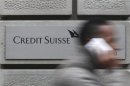 A man uses his cell phone as he walks past a branch of Swiss bank Credit Suisse in Zurich