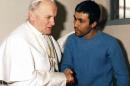 FILE - In this Dec. 27, 1983 file photo provided by Vatican newspaper L'Osservatore Romano, Pope John Paul II, left, meets Mehmet Ali Agca, in Agca's prison cell in Rome. The Vatican says the Turk who shot and wounded John Paul II in 1981 has laid flowers on the saint's tomb in St. Peter's Basilica. A Vatican spokesman, the Rev. Ciro Benedettini, said the surprise visit Saturday by Mehmet Ali Agca lasted a few minutes. As with other flowers left by visitors to the tomb, the white blossoms were later removed by basilica workers. John Paul visited the incarcerated Agca in 1983 and later intervened with Italian authorities to gain Agca's release in 2000 from the Italian prison where he was serving a life sentence for the assassination attempt in St. Peter's Square. (AP Photo/L'Osservatore Romano, File)
