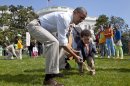 President Barack Obama helps a little boy roll his egg to the finish line during the annual White House Easter Egg Roll, Monday, April 9, 2012, on the South Lawn of the White House in Washington. In the background, at left are Malia Obama and Sasha Obama. (AP Photo/Carolyn Kaster)
