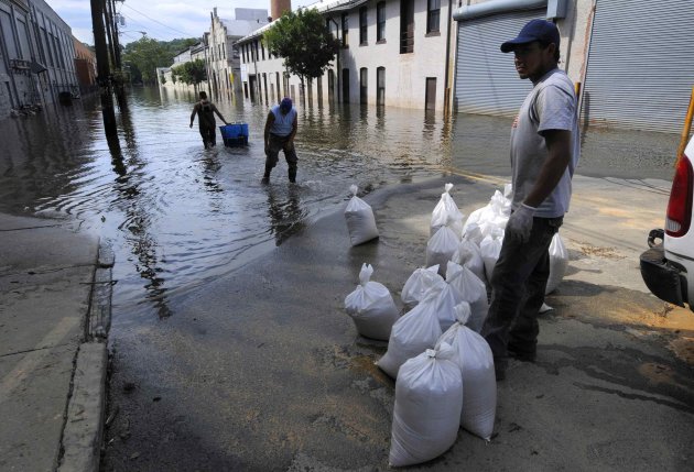 Workers retrieve items from a factory as they put sand bags in place in the flood waters of the Passaic River in Paterson