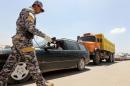 A policeman uses a scanning device to inspect a vehicle at the entrance to Sadr City
