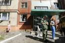 Local residents and a pro-Russian fighter stand near the entrance to an apartment block damaged by shelling in Slaviansk in eastern Ukraine
