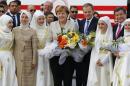 German Chancellor Merkel, EU Council President Tusk and Turkish Prime Minister Davutoglu pose with flowers during a welcoming ceremony at Nizip refugee camp near Gaziantep