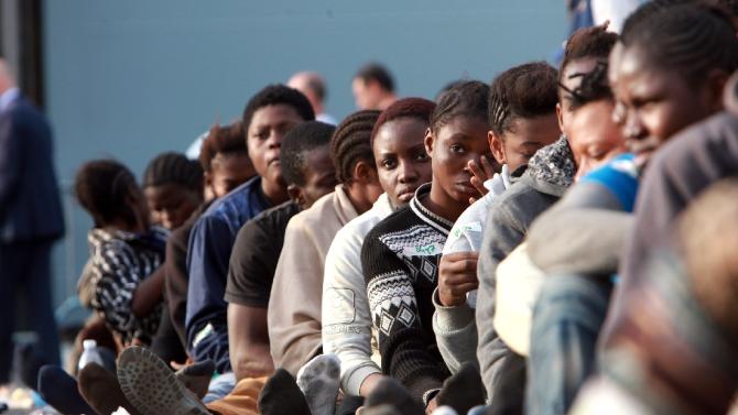 Migrants sit in line after disembarking from the Royal Navy ship HMS &quot;Bulwark&quot; upon arrival in the port of Catania on the coast of Sicily on June 8, 2015