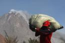 A villager carries his belonging during an evacuation following the eruption of Mount Sinabung in Gamber village, North Sumatra, Indonesia, Sunday, May 22, 2016. The volcano in western Indonesian unleashed hot clouds of ash on Saturday, killing several villagers, oficials said. (AP Photo/Binsar Bakkara)
