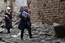 Young Syrian women carry books as they walk through the rubble of destroyed buildings following a reported air strike by Syrian government forces in the rebel-held area of Douma, east of the capital Damascus, on October 29, 2015