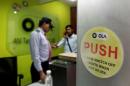 An employee speaks over his phone as a private security guard looks on at the front desk inside the office of Ola cab service in Gurugram
