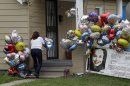 Culema Nevarez adds balloons to a growing tribute outside the home of Gina DeJesus in Cleveland, Friday, May 10, 2013. DeJesus was freed Monday from the home of Ariel Castro where she and two other women had been held captive for nearly a decade. (AP Photo/Mark Duncan)