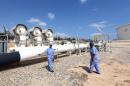 A picture taken on August 22, 2013 in Zawiya shows oil workers from the Libyan National oil and gas company walking at the the Zawiya oil installation