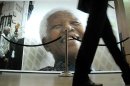 People pass photos of former South Africa President Nelson Mandela at the Nelson Mandela Legacy Exhibition in Cape Town, South Africa, Tuesday, July 2, 2013. Mandela remains in critical condition in a Pretoria clinic . (AP Photo/Masixole Feni)