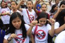 Filipino Christian youths flash the thumbs-down signs as they chant 