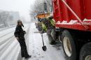 Crew members work on salt trucks as the snow begins to fall in Washington