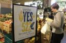 A customer picks up produce near a sign supporting a ballot initiative in Washington state that would require labelling of foods containing genetically modified crops at the Central Co-op in Seattle, Washington