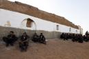 Members of the Sahrawi People's Liberation Army sit waiting outside a building during the Polisario Front's extraordinary congress on July 8, 2016