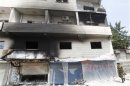 A Syrian soldier walks near a burning building at Haffeh town near Latakia city