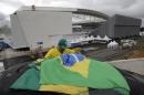A Brazilian fan tries to tie his country's flag on top of his car, outside Arena de Sao Paulo, Brazil, on Tuesday, June 10, 2014. The World Cup is set to open on June 12 with Brazil facing Croatia in Sao Paulo. (AP Photo/Thanassis Stavrakis)
