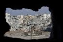 This Nov. 20, 2014 photo shows an area controlled by the Islamic State group, past the Qada Azadi roundabout, foreground, in Kobani, Syria. Amid the wasteland and destroyed buildings, a sense of camaraderie has developed among the town's defenders who have doggedly fought off militant advances for more than two months. (AP Photo/Jake Simkin)