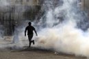 Protester runs with a tear gas canister, which was earlier fired by riot police, during a protest in Cairo