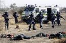 A policeman gestures in front of some of the dead miners after they were shot outside a South African mine in Rustenburg