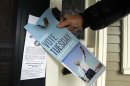 Ewing hangs a piece of campaign literature on a door knob as he canvasses for U.S. President Obama in Portsmouth