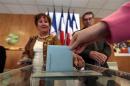 A woman holds her ballot before voting in a polling station during the second round of the French elections in Frejus