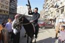 A Free Syrian Army fighter holds up his weapon and rides a horse as people on the first day of Eid al-Adha in Aleppo