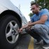 In this Aug. 11, 2011 photo, Jeff Swanson, 25, looks at the rear rotors on his 10-year-old Pontiac Grand Prix in Sterling Heights, Mich. Swanson, who was in the market for a new car just weeks ago, decided to keep his 10-year-old Pontiac Grand Prix for at least another year. Gyrations in stocks and talk of a weakening economy rattled Swanson's confidence about taking on another payment, even though his new job running a home for mentally disabled people seems to be secure. (AP Photo/Paul Sancya)