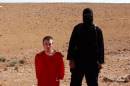 Still image from video shows a masked man standing next to a kneeling man identified as U.S. citizen Peter Edward Kassig