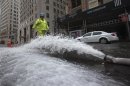 A worker walks past a hose pumping water out of underground parking structures in the financial district of Lower Manhattan, New York