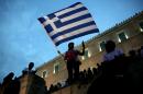 An anti-austerity protester holds a Greek flag in front of the parliament during a protest against austerity policies on July 21, 2015