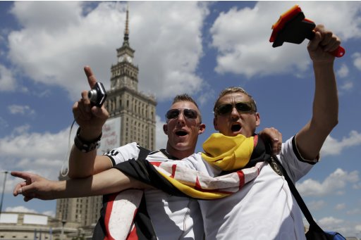 Germany soccer fans cheer as they stand in front of the Palace of Culture in Warsaw