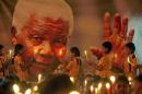 Schoolchildren hold candles near a giant portrait of former South African President Nelson Mandela in Chennai, India, Friday, Dec. 6, 2013. Mandela, who died Dec. 5 at age 95, was considered a master of forgiveness. He became South Africa's first black president after spending nearly a third of his life as a prisoner of apartheid. (AP Photo/Arun Sankar K)