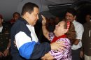 In this photo provided by Miraflores Presidential Press Office, Venezuela's President Hugo Chavez, left, embraces his mother Helena Frias as she reaches to touch his forehead as she welcomes him home at the airport in Barinas, Venezuela, Wednesday April 4, 2012. Chavez returned to Venezuela on Wednesday night after his latest round of radiation therapy treatment in Cuba. (AP Photo/Miraflores Presidential Office)