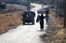 Residents walk on a street in al-Ghab plain in the Hama countryside