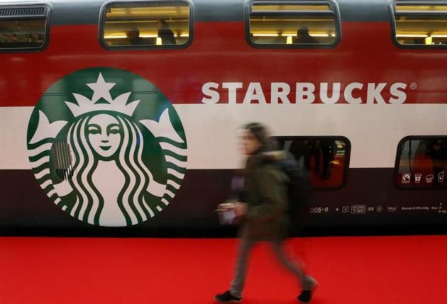 A woman walks past a Starbucks logo painted on a railway coach at the main train station in Zurich November 14, 2013. REUTERS/Arnd Wiegmann