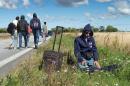A migrant prays on the side of a road north of Rodby as a large group walks on the highway moving towards Sweden on September 7, 2015