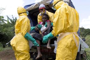 Health workers wearing protective suits assist a patient …