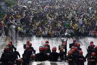 Malaysian activists from Coalition for Clean and Fair Elections (Bersih), background, sit on a street as they face riot police during a rally in Kuala Lumpur, Malaysia, Saturday, July 9, 2011. Police fired tear gas and detained hundreds of activists as those demonstrators massed Saturday across Malaysia's main city demanding electoral reforms in the country's biggest political rally in years. The "Bersih" means "clean" in Malay. (AP Photo/Vincent Thian)
