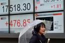 A reporter stands near a share prices board in Tokyo on January 29, 2016