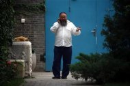 Chinese dissident artist Ai Weiwei talks on his mobile phone as he walks near the entrance to his studio in Beijing June 20, 2012. REUTERS/David Gray
