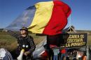 A man holds Romania's national flag in front of a tent installed on the empty lot where U.S. oil major Chevron plans to search for shale gas in Pungesti