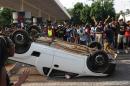Students from the University of the Witwatersrand overturn a vehicle off campus after blocking traffic, during protests in Johannesburg, Monday Oct. 19 2015. Students, demonstrating against the increase of tuition fees at some top South African universities, blocked roads and entrances and caused the suspension of classes on some campuses. (AP Photo)