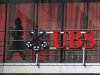 Woman walks past a logo of Swiss bank UBS at a building in Zurich